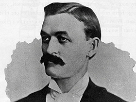 Monochromatic photograph of a George Ferris with a mustache.
