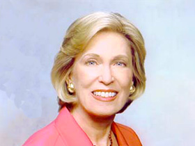 Barbara Franklin, wearing a pink jacket and necklace, in a professional photo.