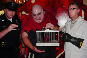A caged blob held by costumed revelers