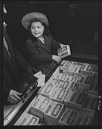 A girl holding frozen food while her mother looks at her ration book in World War II